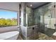 Stunning bathroom featuring soaking tub, slate tile, and glass-enclosed shower offering views of the surrounding landscape at 39810 N 105Th Way # 128, Scottsdale, AZ 85262