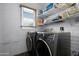 Laundry room featuring modern washer and dryer with white brick walls and shelving at 654 W Plata Ave, Mesa, AZ 85210
