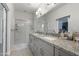 Bathroom features dual sinks with granite countertops and a glass-enclosed shower with white tiled walls at 7531 E Billings St # 116, Mesa, AZ 85207