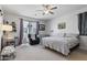 Bedroom featuring a queen-sized bed, ceiling fan, and seating area beneath a window with purple curtains at 7531 E Billings St # 116, Mesa, AZ 85207