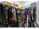 Walk-in closet with wood shelving and bars, clothes, and storage boxes at 7531 E Billings St # 116, Mesa, AZ 85207