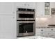 Modern kitchen with stainless steel double oven, white subway tile backsplash, and white cabinets at 9059 E Leonora St. St, Mesa, AZ 85207