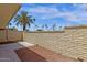 Backyard patio featuring concrete and red rock surfaces, along with a brick wall and a palm tree at 9707 W Lancaster Dr, Sun City, AZ 85351