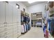 An organized walk-in closet featuring extensive shelving, cabinets, hanging racks, and a neutral-toned carpet for storage and functionality at 9820 E Thompson Peak Pkwy # 628, Scottsdale, AZ 85255