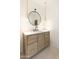Modern bathroom vanity with round mirror, pendant lights, and wooden cabinetry providing stylish functionality at 10795 E Sutherland Way, Scottsdale, AZ 85262