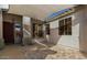 Covered patio area featuring a shade sail, stone flooring and a wooden front door at 13628 W San Miguel Ave, Litchfield Park, AZ 85340