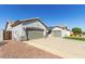 Exterior view of the home, showing the two-car garage, desert landscaping, and side gate at 13628 W San Miguel Ave, Litchfield Park, AZ 85340