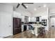 Modern kitchen boasts white cabinetry, stainless steel appliances, island with seating, and sleek black backsplash at 13628 W San Miguel Ave, Litchfield Park, AZ 85340