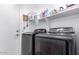Well-organized laundry room with modern washer and dryer, storage shelves, and convenient access to utilities at 13628 W San Miguel Ave, Litchfield Park, AZ 85340