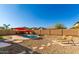 Enjoy the Arizona sun in this desert backyard with pool, rock features, and lounge chairs, shaded by red umbrellas at 13628 W San Miguel Ave, Litchfield Park, AZ 85340
