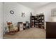 Versatile bedroom area with dark wood desk, chair, shelving and a comfy rocking chair in neutral colors at 24327 N 163Rd Dr, Surprise, AZ 85387