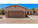 Home with a brown two-car garage and desert landscaping under a blue sky in a well-maintained community at 2635 E Riviera Dr, Chandler, AZ 85249