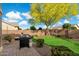 Landscaped backyard with a lush lawn, mature tree, brick walls, and a barbecue grill at 3003 E Ironside Ln, Gilbert, AZ 85298