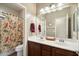 Well-lit bathroom with a double sink vanity, floral shower curtain and a large mirror at 3003 E Ironside Ln, Gilbert, AZ 85298