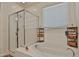 Bright bathroom featuring a glass-enclosed shower, soaking tub, and elegant fixtures and neutral decor at 3319 W Carter Rd, Phoenix, AZ 85041