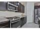 Close-up of a modern kitchen featuring stainless steel appliances, granite countertops, and dark wood cabinetry at 3319 W Carter Rd, Phoenix, AZ 85041