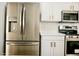Updated kitchen features stainless steel fridge, modern white cabinets with brass hardware, and sleek countertops at 365 E Mountain View Rd, San Tan Valley, AZ 85143