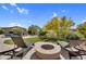 Beautiful backyard featuring a stone fire pit with lounge chairs, artificial turf, and mature desert landscaping at 37308 N 100Th Pl, Scottsdale, AZ 85262