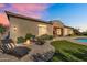 Inviting backyard featuring a fire pit, lounge chairs, and well-maintained landscaping under a colorful evening sky at 37308 N 100Th Pl, Scottsdale, AZ 85262