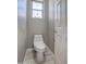 A modern, white toilet is displayed in a small bathroom with a patterned glass window and wood look flooring at 40741 N Citrus Canyon Trl, Anthem, AZ 85086