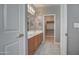 Modern bathroom with double sinks, wood cabinet and light tile flooring, with view of closet at 40741 N Citrus Canyon Trl, Anthem, AZ 85086