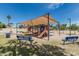 Community playground featuring slides, swings, and climbing structures under a shaded canopy, with benches for parents at 620 N Entrada St, Chandler, AZ 85226