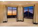 A spacious bedroom showcases stunning city views through large windows, complemented by elegant drapery and plush carpeting at 7175 E Camelback Rd # 902, Scottsdale, AZ 85251