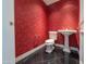 Stylish powder room with red wallpaper, pedestal sink, and black tile flooring at 7175 E Camelback Rd # 902, Scottsdale, AZ 85251
