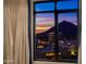 A beautiful window view with curtains showcases a stunning sunset and city lights, creating a serene ambiance at 7175 E Camelback Rd # 902, Scottsdale, AZ 85251