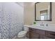 Well-lit bathroom featuring a shower/tub combo with a stylish shower curtain, modern vanity, and a large mirror at 15324 W Windsor Ave, Goodyear, AZ 85395