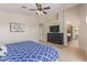 Bedroom featuring blue bedding, carpet flooring, and ceiling fan with television and view into adjoining room at 15324 W Windsor Ave, Goodyear, AZ 85395