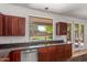 Kitchen area with stainless steel dishwasher, granite countertops, dark wood cabinets and view of pool at 2036 S Reseda Ct, Gilbert, AZ 85295