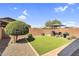 Charming backyard featuring a cozy lounge area, privacy wall, and an easy to maintain artifical lawn at 22560 E Rosa Rd, Queen Creek, AZ 85142