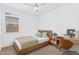 Staged bedroom with natural wood bedframe, desk, and ceiling fan at 22560 E Rosa Rd, Queen Creek, AZ 85142