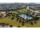 View of a community pool with a clubhouse and palm trees amidst lush landscaping in a residential neighborhood at 22560 E Rosa Rd, Queen Creek, AZ 85142
