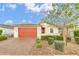 Charming single-story home with a red garage door, desert landscaping, and a paver driveway at 22560 E Rosa Rd, Queen Creek, AZ 85142