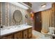 Bathroom featuring patterned wallpaper, an oval mirror, and wood vanity at 3160 E Main St # 110, Mesa, AZ 85213