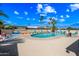 Outdoor community pool with lounge chairs under a partly cloudy sky, surrounded by mature palm trees at 3160 E Main St # 110, Mesa, AZ 85213