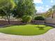 Landscaped backyard featuring artificial turf, mature trees, and a brick paver patio at 3221 E Lynx Pl, Chandler, AZ 85249