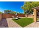 A backyard with a privacy wall, artificial grass, gravel, and a pair of lounge chairs at 4034 E Mine Shaft Rd, San Tan Valley, AZ 85143