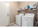 Functional laundry room with white appliances, shelving, and ample space, making laundry tasks efficient and organized at 4034 E Mine Shaft Rd, San Tan Valley, AZ 85143