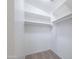 Bright walk-in closet with ample white shelving for organized storage and carpet at 41388 W Hopper Dr, Maricopa, AZ 85138