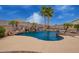 Backyard pool and spa with lush landscaping, rock waterfall, and mature palm trees at 5510 N 132Nd Dr, Litchfield Park, AZ 85340