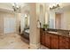 Large bathroom with tile floors, dual vanities, and a tub with stone tile on the exterior at 7425 W Caro Rd, Glendale, AZ 85308