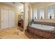 Bright bathroom with marble tile floors, a tub with steps, and a vanity with granite counters at 7425 W Caro Rd, Glendale, AZ 85308