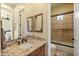 Bathroom featuring double mirrors above a granite vanity, a walk-in shower with glass doors, and neutral colors at 7425 W Caro Rd, Glendale, AZ 85308