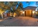 Well-lit driveway leading to a two-car garage, surrounded by mature trees and low-maintenance landscaping at 7425 W Caro Rd, Glendale, AZ 85308