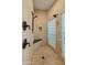 Detailed view of the beige tiled shower with a bench, glass block windows, and bronze fixtures at 7425 W Caro Rd, Glendale, AZ 85308