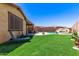 Lush backyard featuring artificial grass, pool with slide, and a covered patio; perfect for outdoor living at 8418 W Palmaire Ave, Glendale, AZ 85305