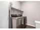 Well-lit laundry room featuring modern silver washer and dryer, complemented by wooden floors and convenient upper shelf at 8418 W Palmaire Ave, Glendale, AZ 85305
